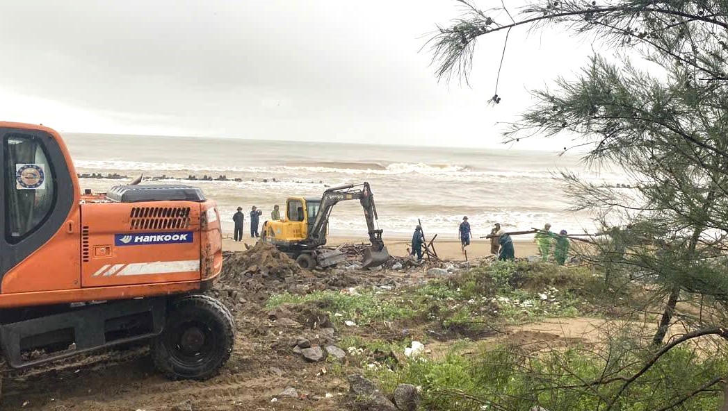 Giữa thời tiết mưa phùn, các lực lượng tích cực thực hiện các biện pháp để gia cố đê. Ảnh: ĐH.