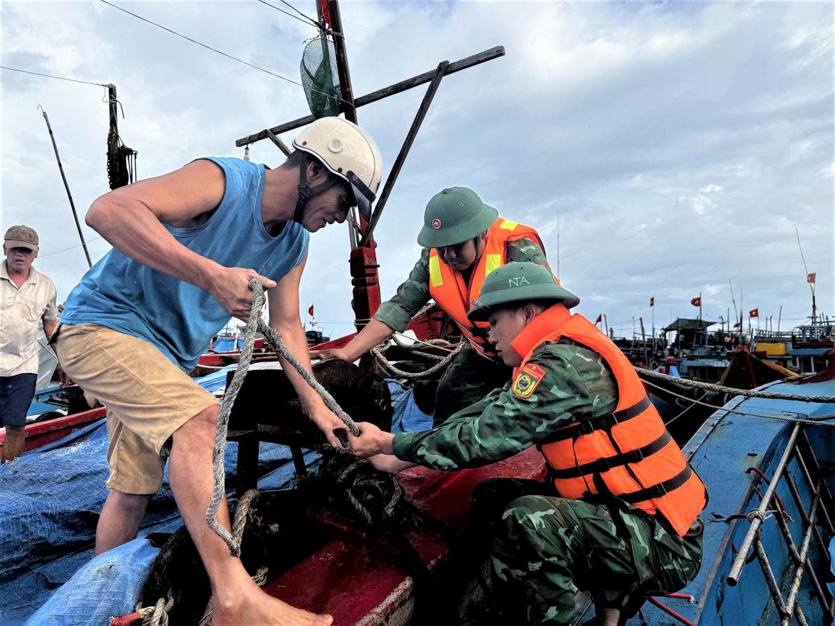 Lực lượng Đồn biên phòng Lý Sơn giúp ngư
dân cột dây neo đậu tàu thuyền. Ảnh: CV.
