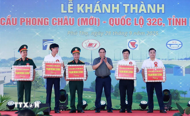 Thủ tướng Phạm Minh Chính tặng quà cho nhà thầu và các đơn vị thi công dự án cầu Phong Châu mới. (Ảnh: Dương Giang/TTXVN).