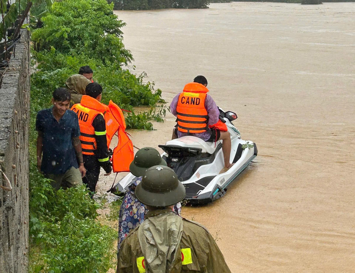 Cảnh sát điều động cano, đưa 13 người mắc kẹt ở trại lợn xã Ngọc Lặc ra ngoài. Ảnh: CATH.