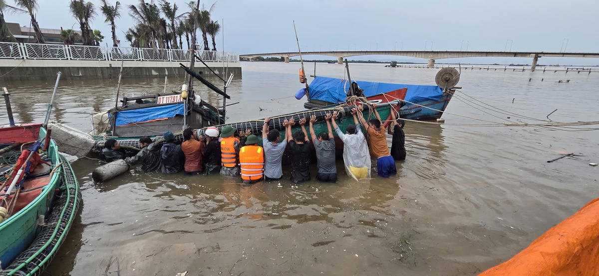 Cán bộ chiến sĩ Biên phòng người dân thu ngư lưới cụ và kéo tàu bị chìm lên bờ. Ảnh: BPCC.