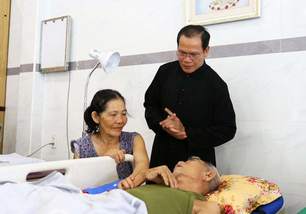 Linh mục Antôn Nguyễn Chân Hồng thăm hỏi bệnh nhân điều trị ở phòng khám Thiên An (do các tu sĩ thuộc Dòng Trợ thế Thánh Gioan Thiên Chúa điều hành tại tỉnh Đồng Nai). Ảnh: Hoàng Anh.