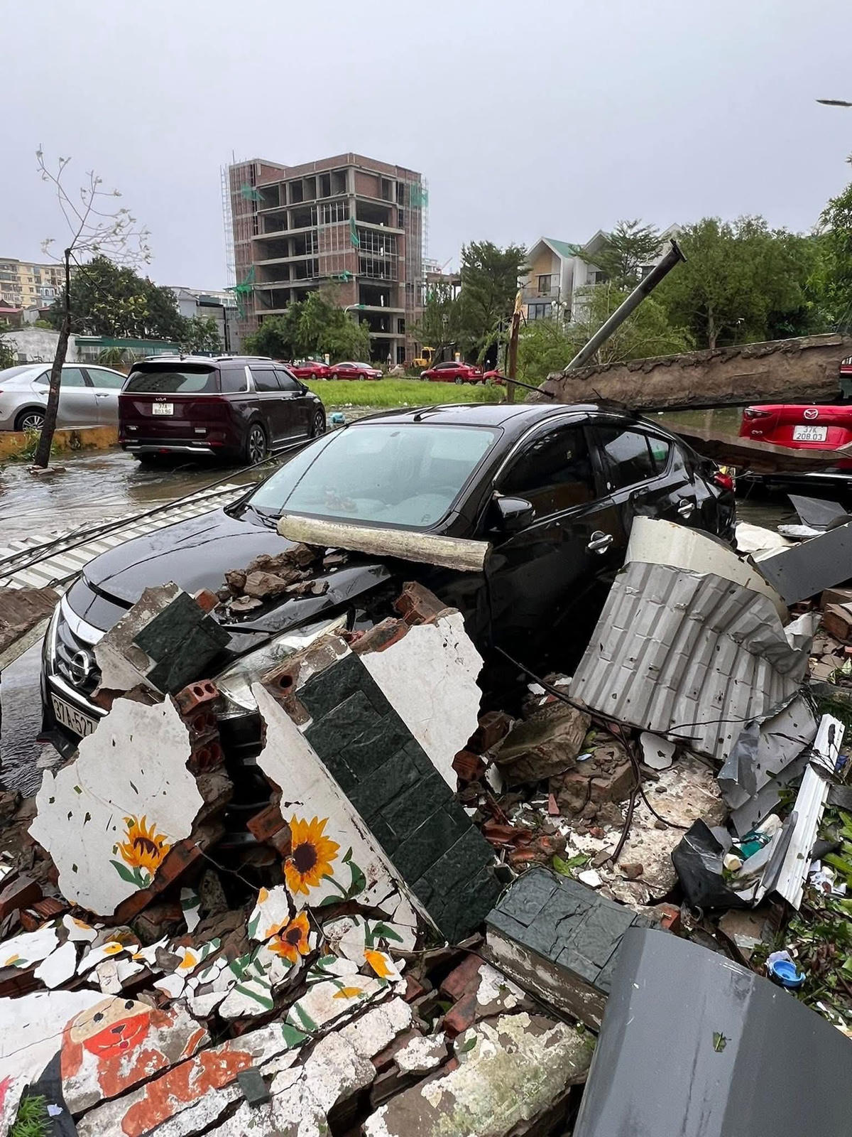 Một bức tường đổ sập khiến 1 chiếc xe ô tô đậu canh bên bị vùi lấp. Ảnh: CV.