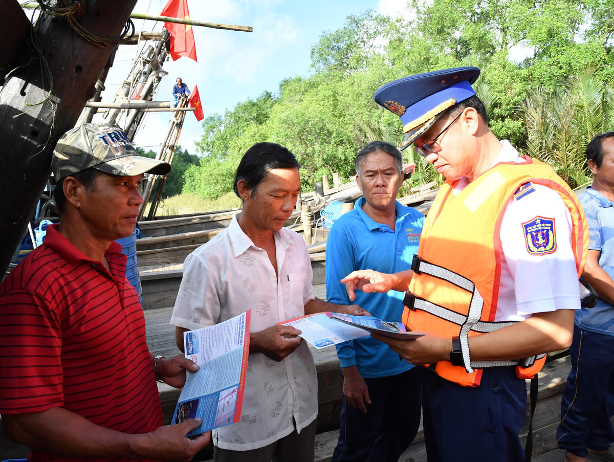 Cảnh sát biển Vùng 3 phát tờ rơi tuyên truyền và túi thuốc cho ngư dân. Ảnh: Đức Định.