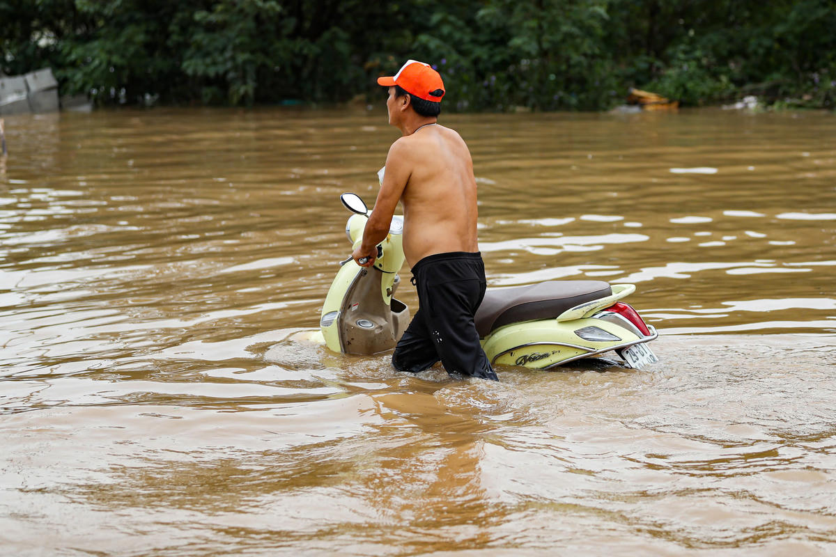 Do xe đã chết máy, người dân chấp nhận cùng xe vượt qua vùng ngập.