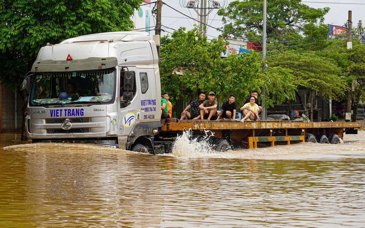 Nhiều người dân đi nhờ xe tải qua vùng ngập úng.