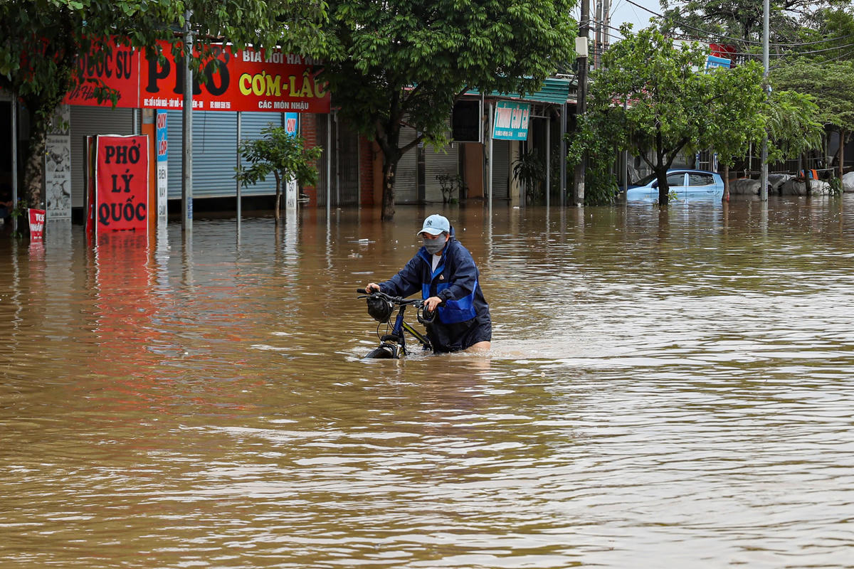 Người dân vất vả dắt xe qua vùng nước ngập.