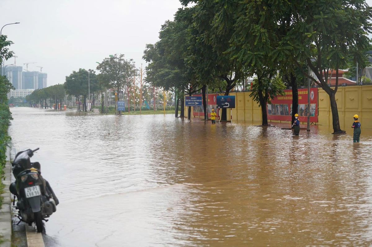 Để nước nhanh chóng thoát, công nhân thoát nước ứng trực tại khu vực đường gom Đại lộ Thăng Long.