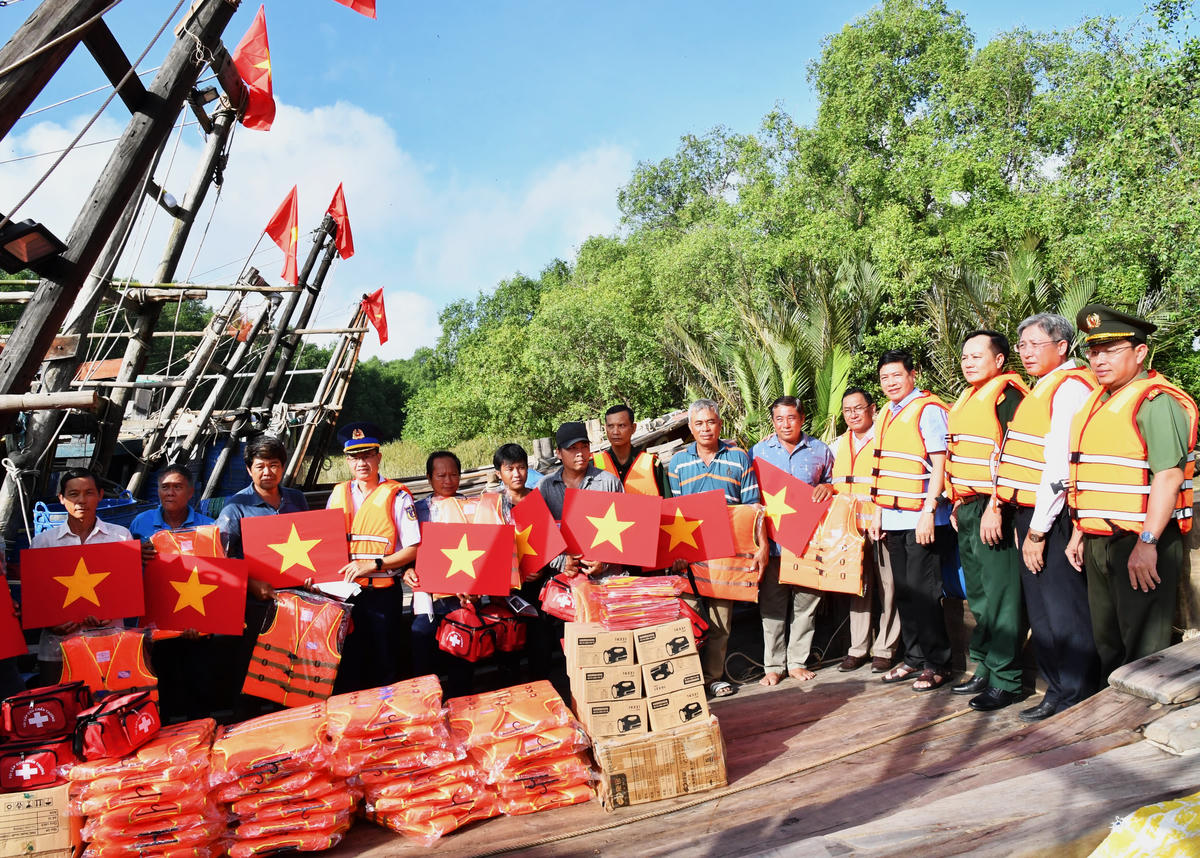 Tặng cờ Tổ quốc, nhu yếu phẩm, túi thuốc y tế cho ngư dân. Ảnh: Đức Định.