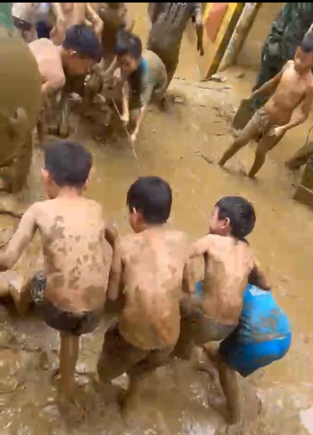 Các em học sinh người đầy bùn, tham gia dọn bùn đất. Ảnh: Ngô Hùng.