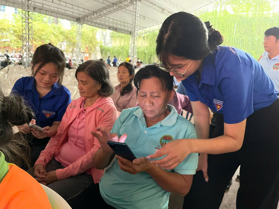 Đoàn viên thanh niên hướng dẫn người cao tuổi sử dụng các ứng dụng hành chính công trên điện thoại tại sự kiện. Ảnh: H. A.