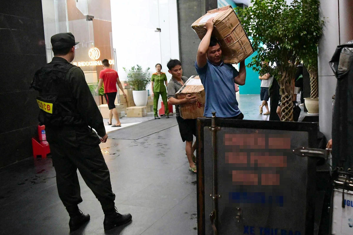 Nhiều thùng tài liệu được chuyển đi từ công ty NextTech trước sự giám sát của công an, tối 7/10. Ảnh: Linh Đan.