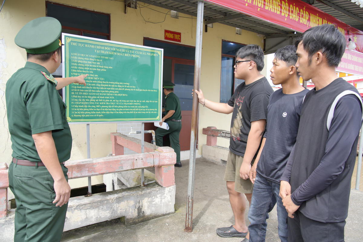 Cán bộ Trạm kiểm soát Biên phòng Kênh Dài, Ban Chỉ huy Bộ đội Biên phòng tỉnh An Giang&nbsp; hướng dẫn ngư dân tìm hiểu các quy định của pháp luật trước lúc ra khơi. (ảnh: Tiến Vinh)