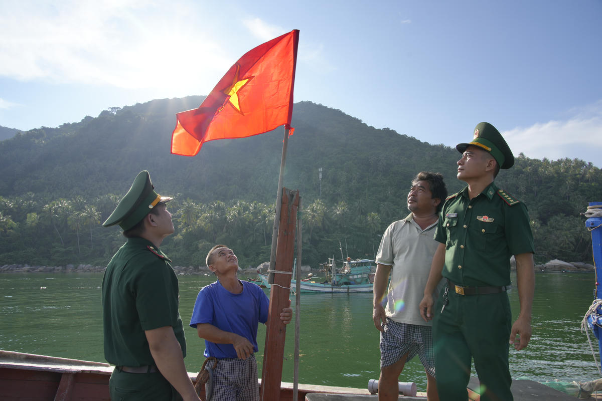Cán bộ đồn Biên phòng Hòn Sơn, thay cờ tổ quốc trên tàu cá, chúc ngư dân vươn khơi đánh bắt đúng pháp luật. (ảnh: Tiến Vinh)