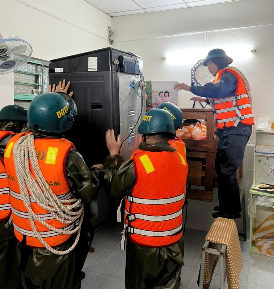 Lực lượng chức năng phường Hòa Khánh đưa đồ đạc của người dân bị ngập nước lên vị trí cao. Ảnh: CV.
