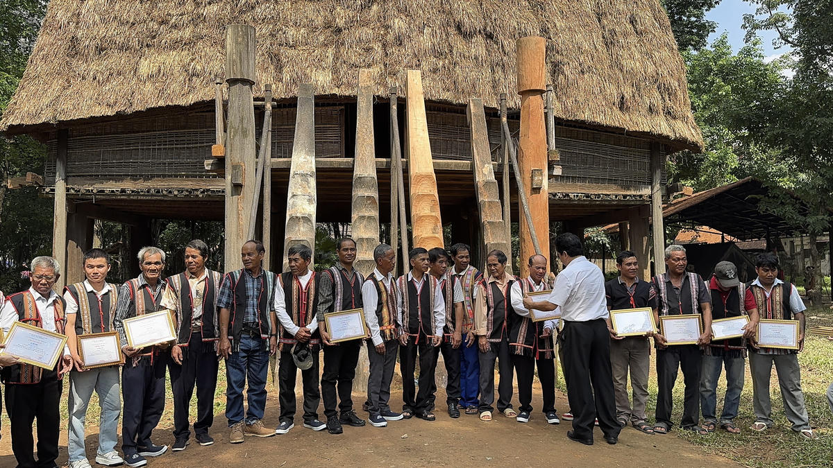 Lãnh đạo Bảo tàng DTHVN trao chứng nhận cho những người Bana tham gia sửa nhà rông. Ảnh: BTC.
