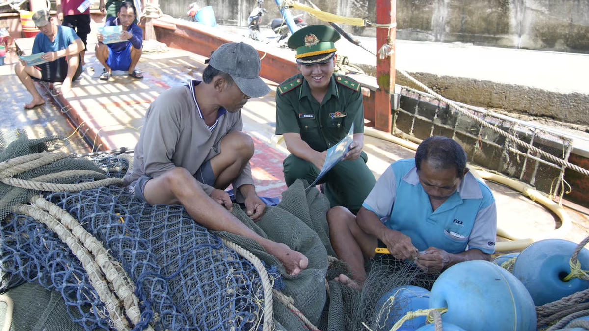 Cán bộ Đồn Biên phòng Gành Dầu (An Giang) phát tờ rơi cho chủ tàu, tài công nội dung liên quan đến chống khai thác IUU. (Ảnh: Tiến Vinh).. 