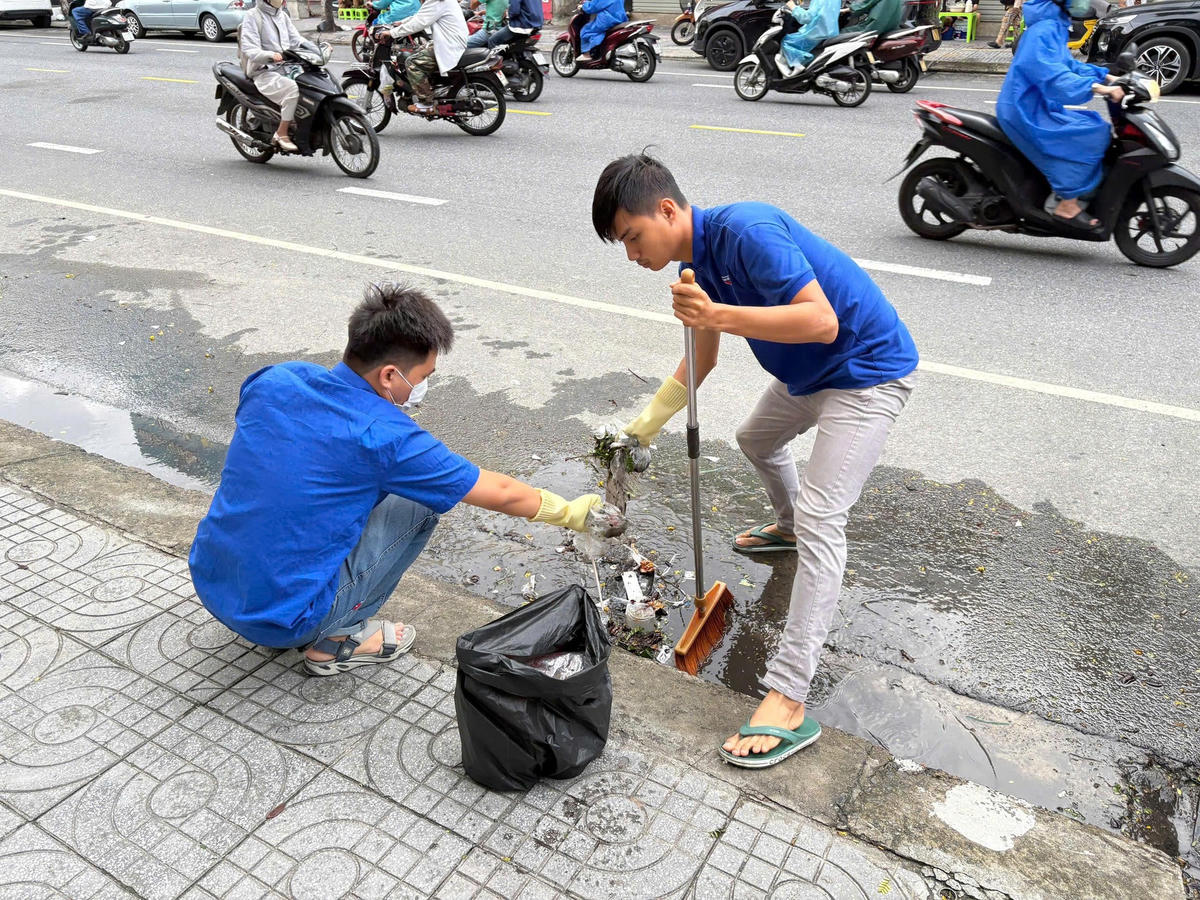 Đoàn thanh niên dọn vệ sinh các miệng cống để thoát nước. Ảnh: Nguyễn Tú