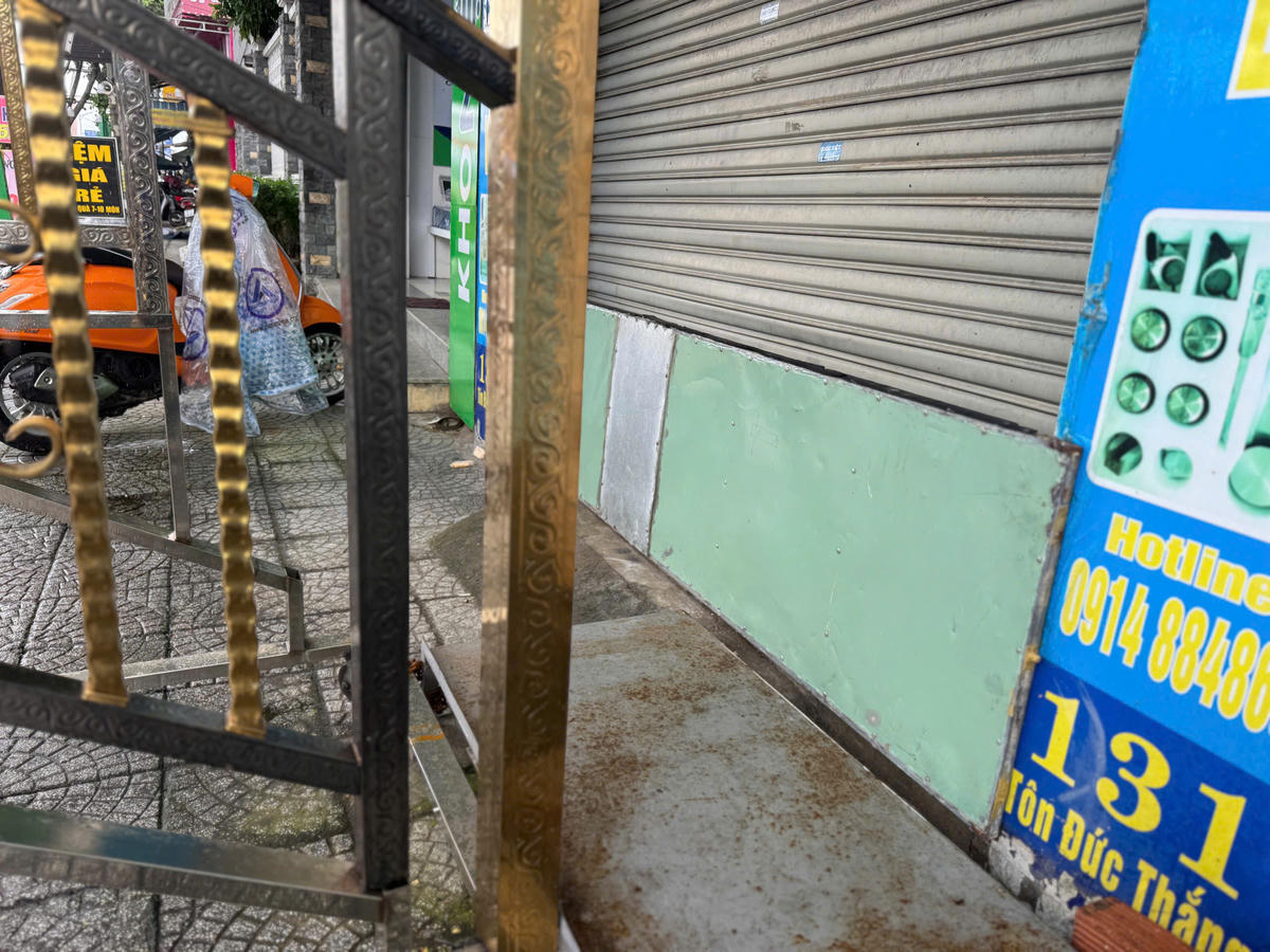 Cơ sở kinh doanh mặt tiền Tôn Đức Thắng dùng đồ chặn cửa để ngăn nước tràn vào khu mưa lớn, ngập nặng.&nbsp;Ảnh: Nguyễn Tú