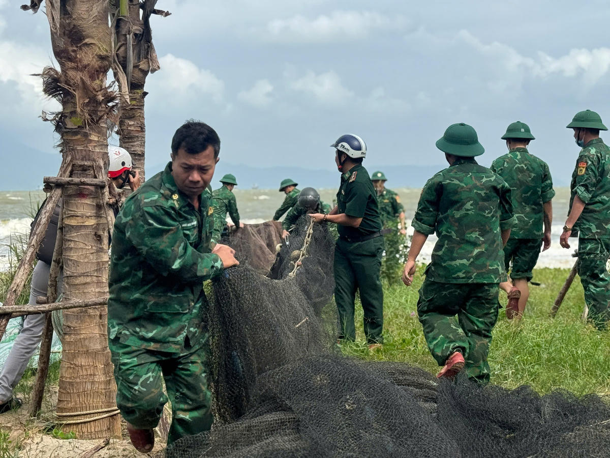 Lực lượng biên phòng giúp dân đưa ngư lưới cụ vào bờ. Ảnh: Nguyễn Tú