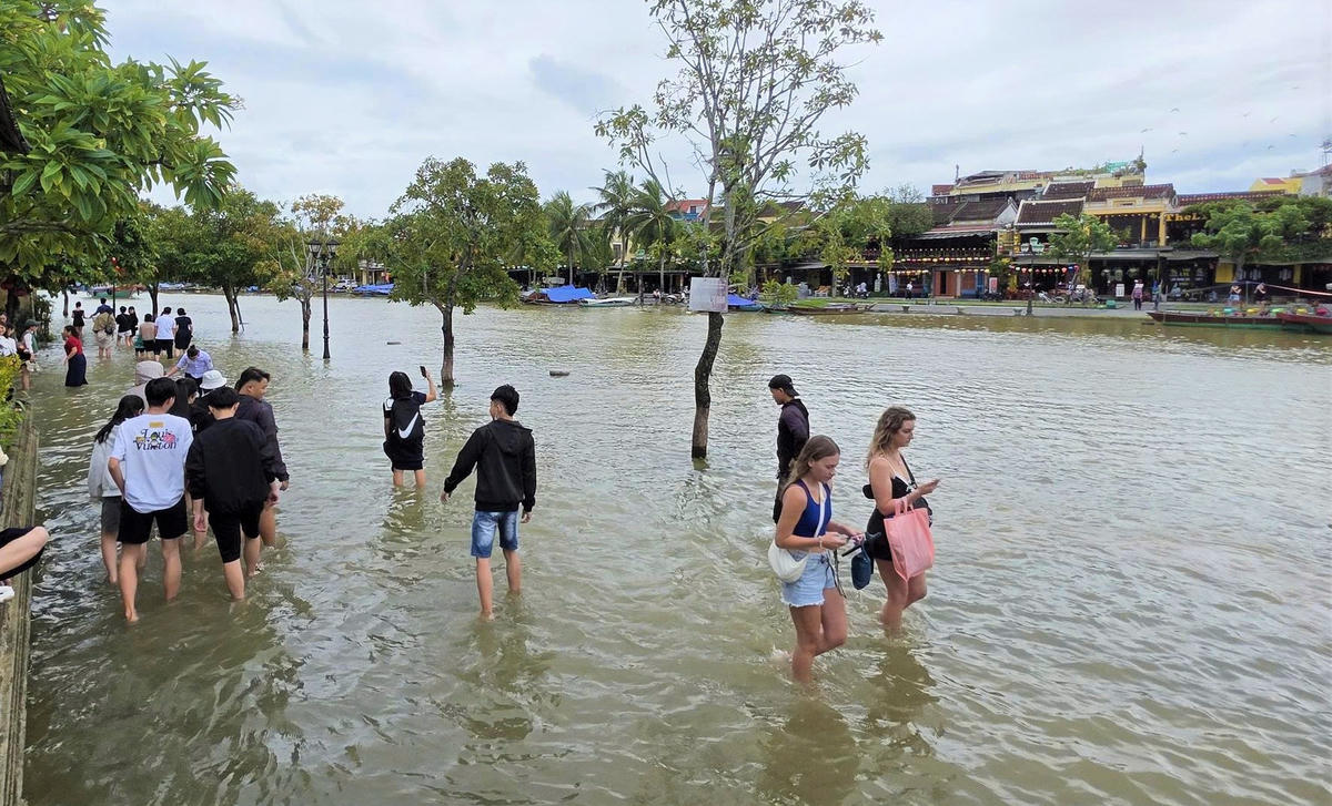 Du khách nước ngoài lội nước check in tại đoạn đường Bách Đằng. Ảnh: Nguyễn Tín..