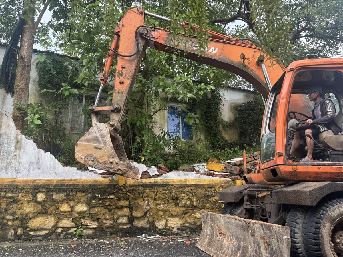 Phá dỡ bờ tường nghiêng, xuống cấp để đề phòng sập đổ gây nguy hiểm cho người dân. Ảnh: Nguyễn Tú.