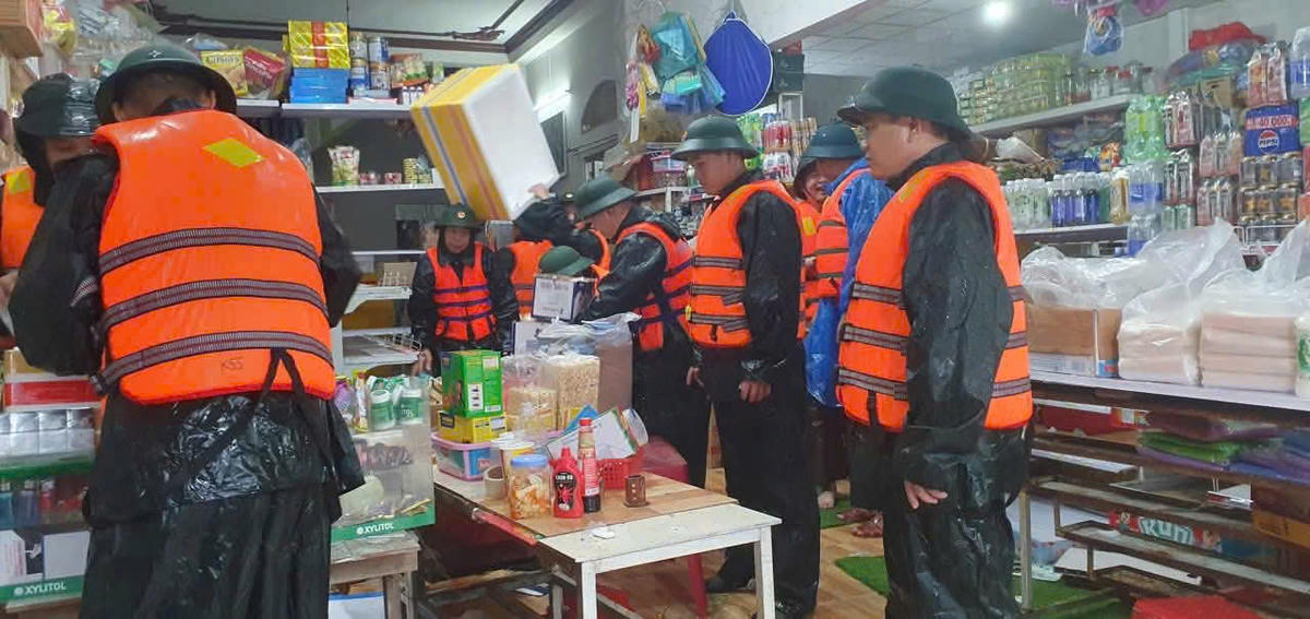 Bộ đội giúp dân di dời tài sản ở tiệm tạp hóa xã Nông Sơn để giảm thiểu thiệt hại do mưa lớn. Ảnh: Quang Hùng.