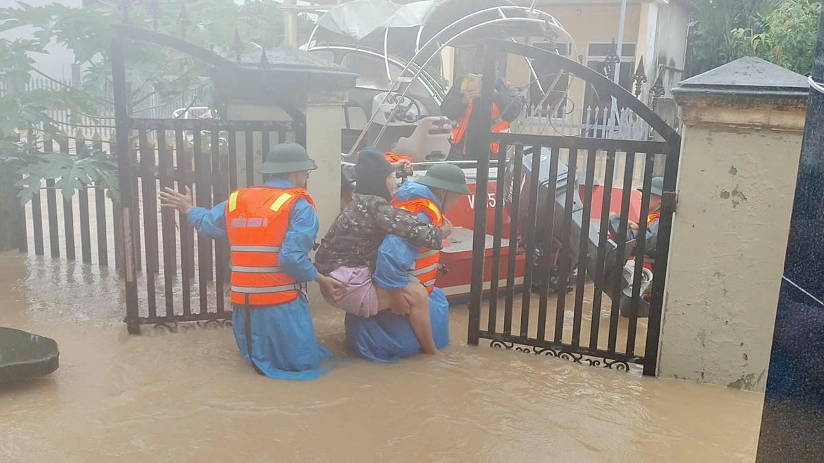 Lực lượng cứu cụ bà mắc kẹt trong nhà ngập nước. Ảnh: Quang Hùng.