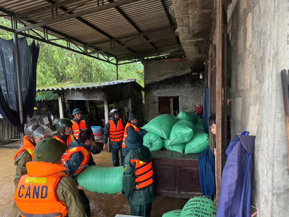 Lực lượng chức năng trợ người dân đưa đồ đạc lên cao đề phòng ngập lụt. Ảnh: T.H.