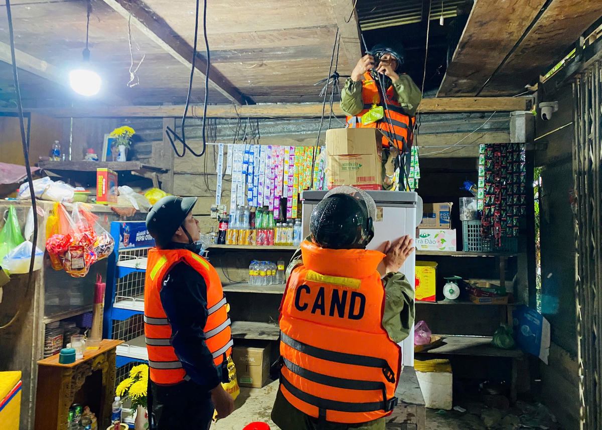 Lực lượng chức năng xã Thượng Đức giúp bà Võ Thị Tứ&nbsp; đưa đồ đạc trong nhà lên vị trí cao. Ảnh: T. Thành.