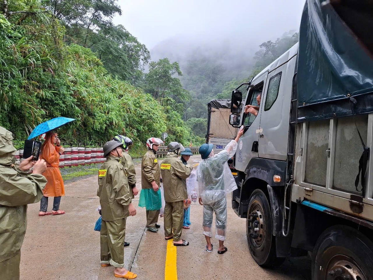 Công an xã xã Phước Năng phối hợp cảnh sát giao thông tặng nước uống, lương thực, mì tôm, bánh mì cho các tài xế và người dân đang mắc kẹt trên đèo. Ảnh: Công an xã.