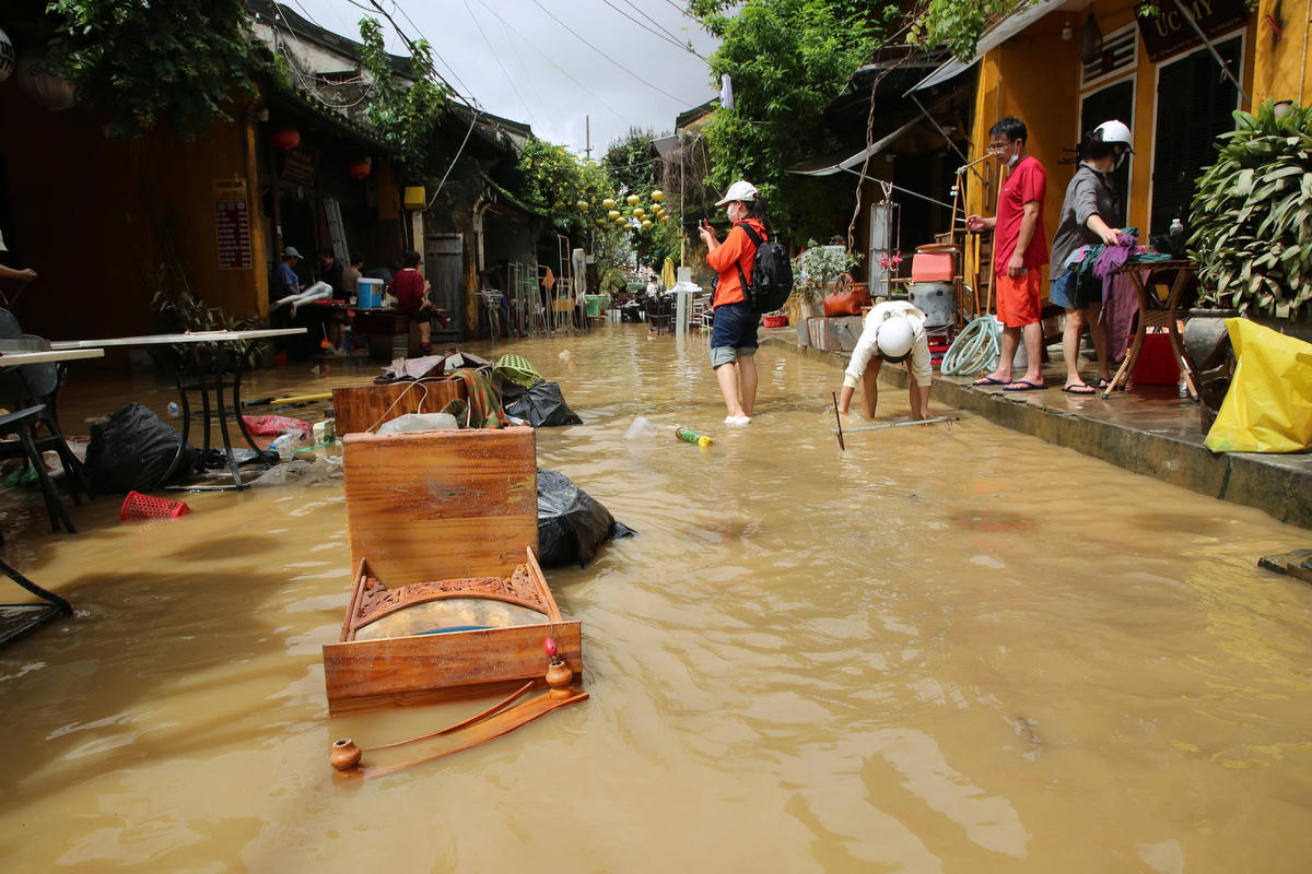 Một du khách (áo màu cam) tham quan phố cổ Hội An chụp ảnh nước ngập vào chiều ngày 31/10. Ảnh Tấn Thành.