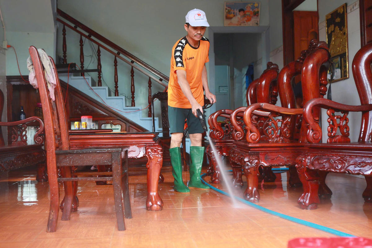 Ông Bùi Tấn Thanh đang dùng voi xịt nước rủa trôi bùn đất bám trong nhà mình. Ảnh: CV.