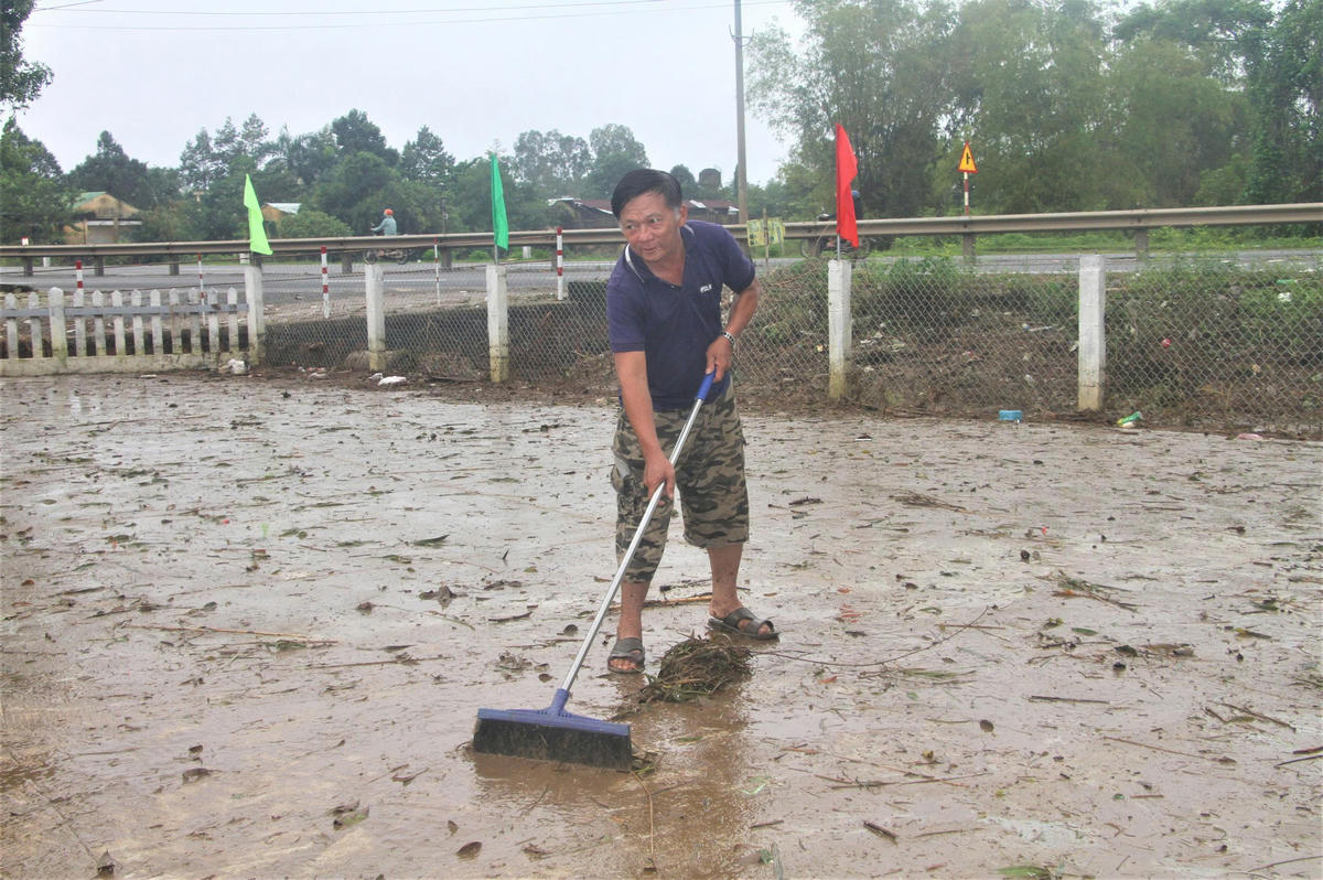 Ông Đặng Văn Sen đang dọn dẹp bùn đất trước sân nhà. Ảnh: Chí Đại. 