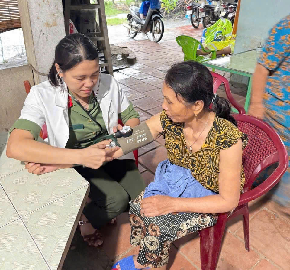 Một trong những chiến sĩ "áo trắng” của Bệnh xá Phòng Hậu cần – Công an TP Đà Nẵng đang khám bệnh cho người dân vùng cô lập vì lũ. Anh: Phước Thành.