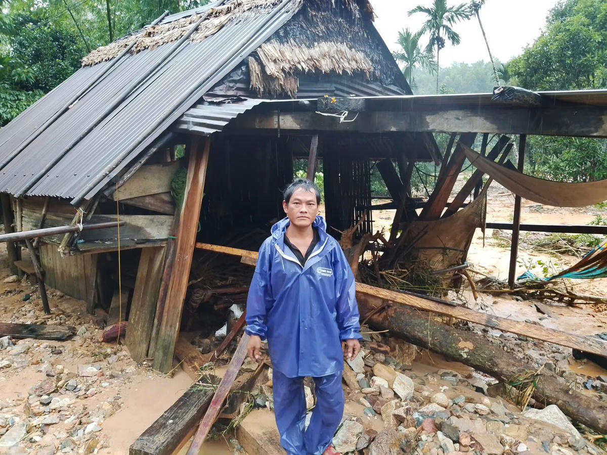 Ông Trần Văn Hán đứng bên cạnh ngôi nhà mình hư hỏng sau lũ quét. Ảnh: CV.