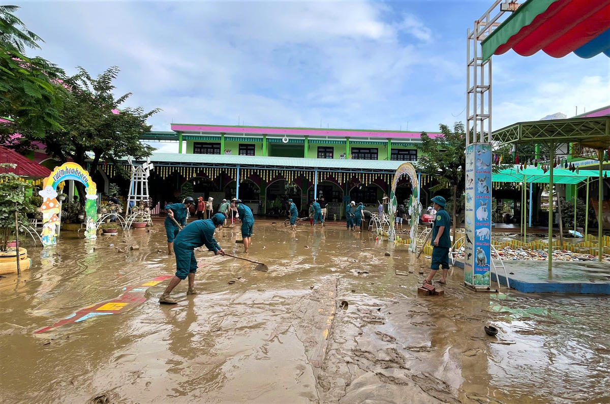 Lực lượng dân quân đang dọn dẹp bùn đất sau khi nước lũ rút xuống tại Trường mầm non Đại An, xã Đại Lộc. Ảnh: CV.
