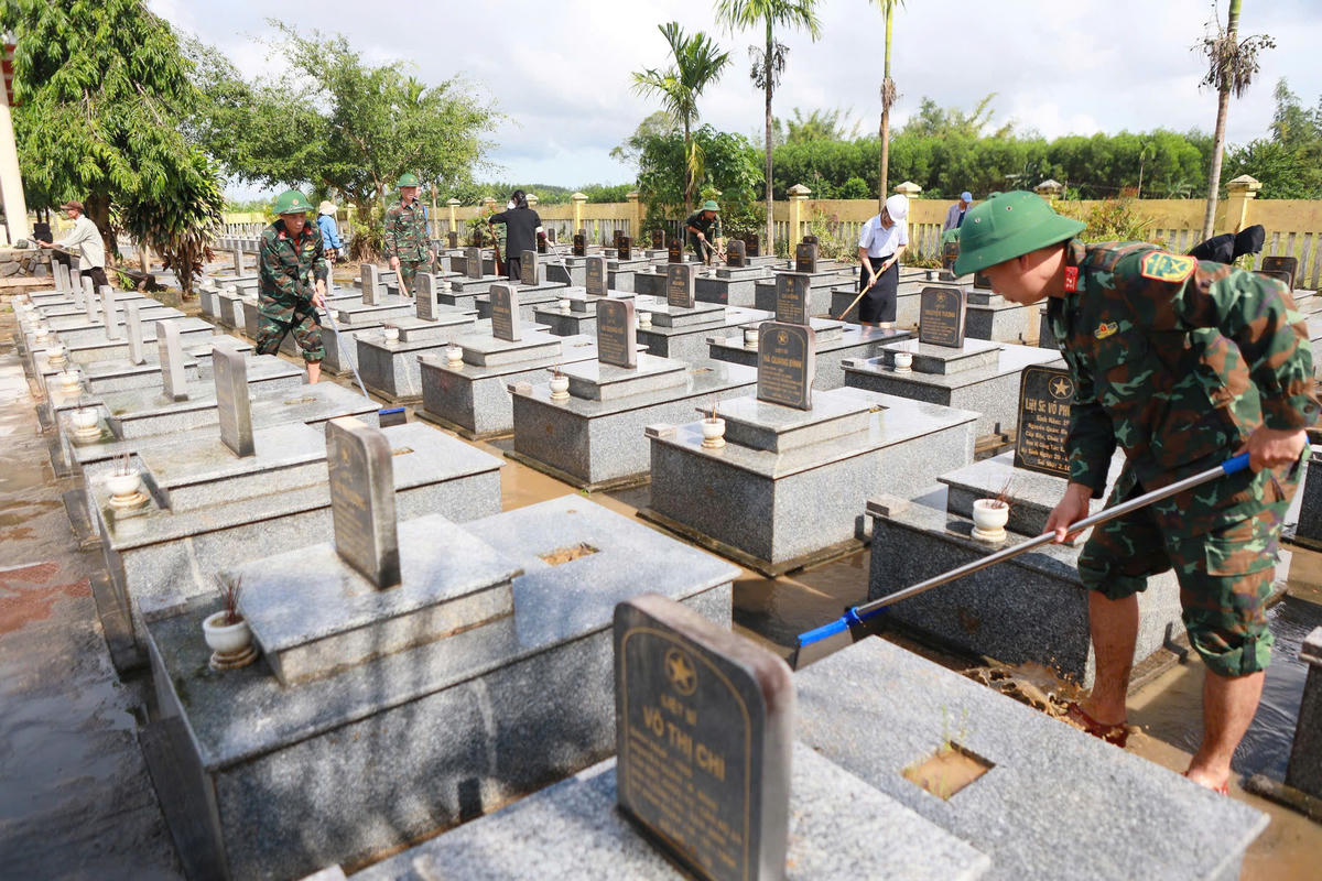 Lực lượng quân đội, người dân dọn dẹp bùn đất sau khi lũ rút xuống tại&nbsp;Nghĩa trang Liệt sĩ xã Bình Minh. Ảnh: CV.