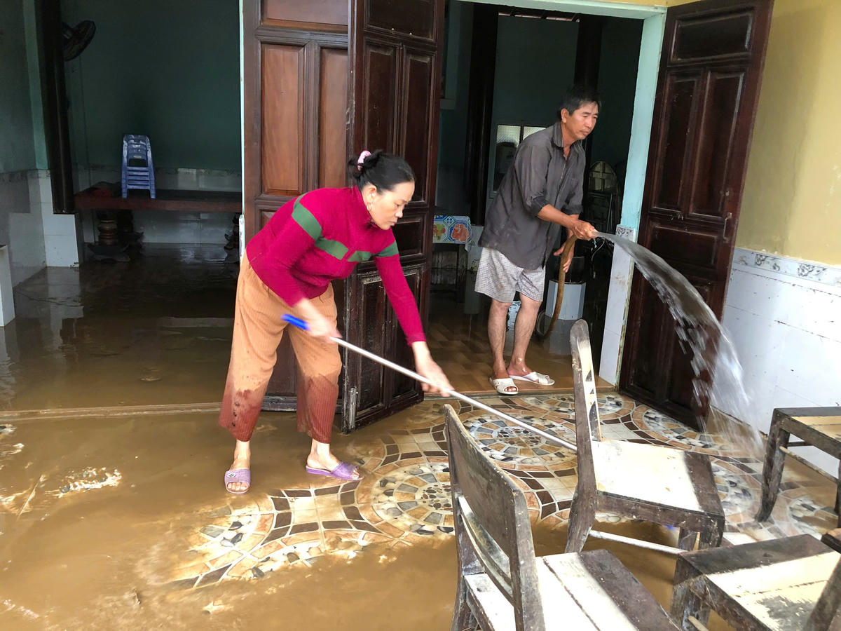 Bà Nguyễn Thị Trinh (áo đỏ) cùng người thân dọn vệ sinh nhà cửa sau khi nước lũ rút xuống. Ảnh: Tấn Thành.&nbsp;&nbsp;