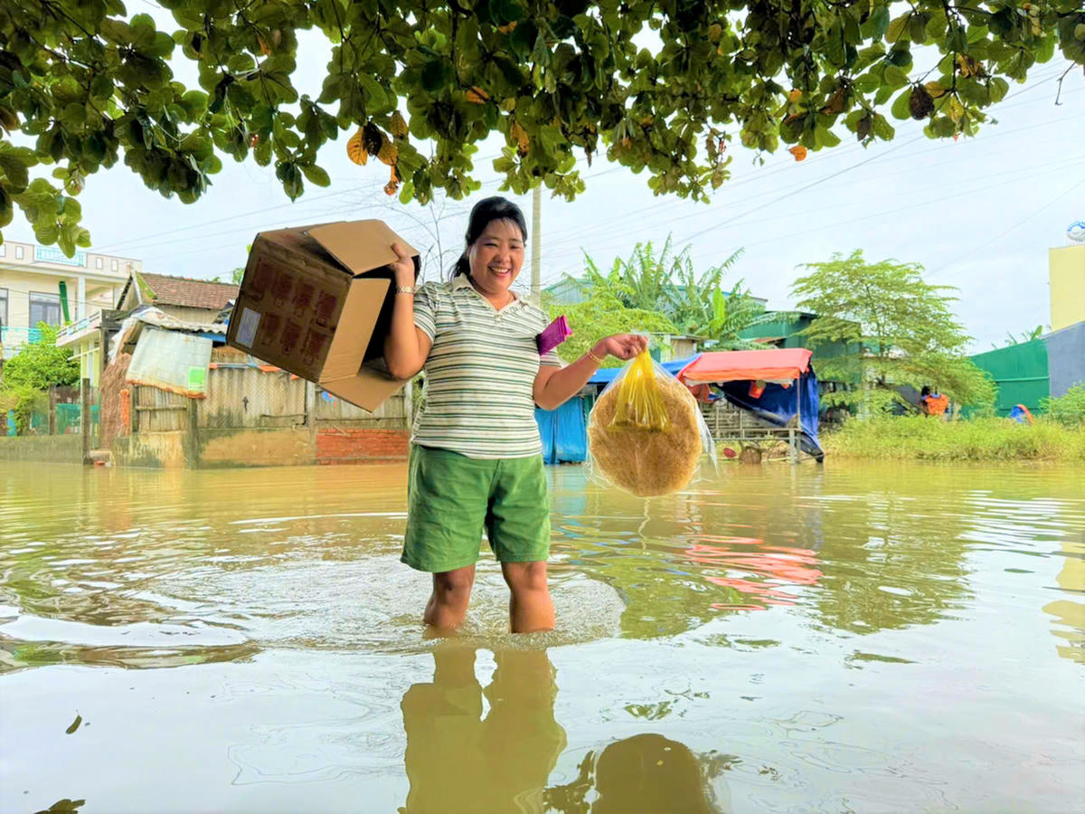 Bà Nguyễn Thị Tính lội nước đi mua thực phẩm cho gia đình. Ảnh: Tấn Thành.