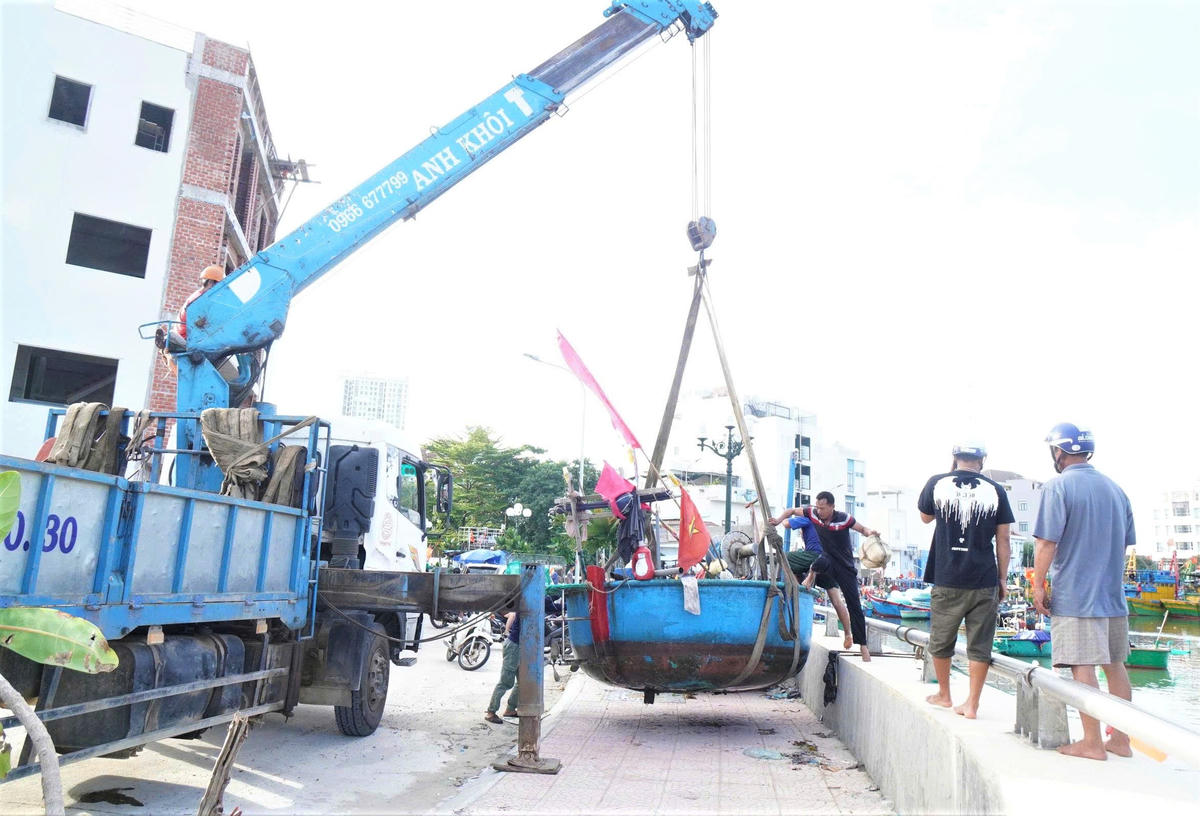 Ngư dân thuê xe cầu ghe lên bờ tránh trú bão số 13 tại cảng Quy Nhơn. Ảnh: T.Thành.