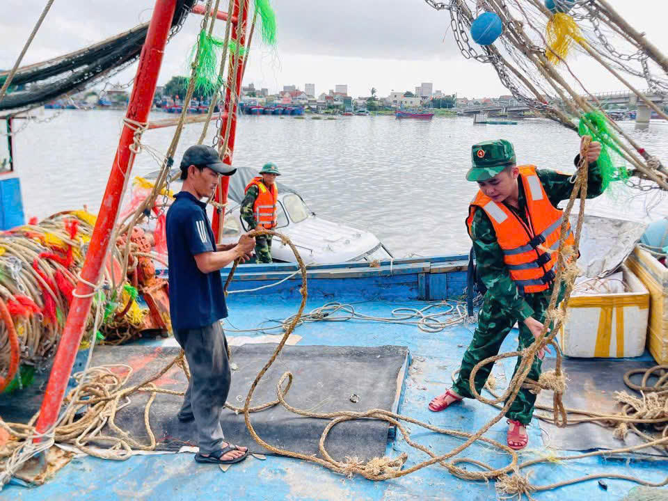 Ngư dân cùng lực biên phòng Quảng Ngãi cột dây tàu thuyền tại bến cảng. Ảnh: CV.