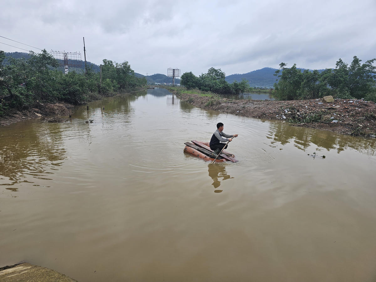 Nhiều tháng nay, anh Nguyễn Doãn Nghĩa phải chèo bè tạm vào trang trại. Ảnh: Quốc Thanh.