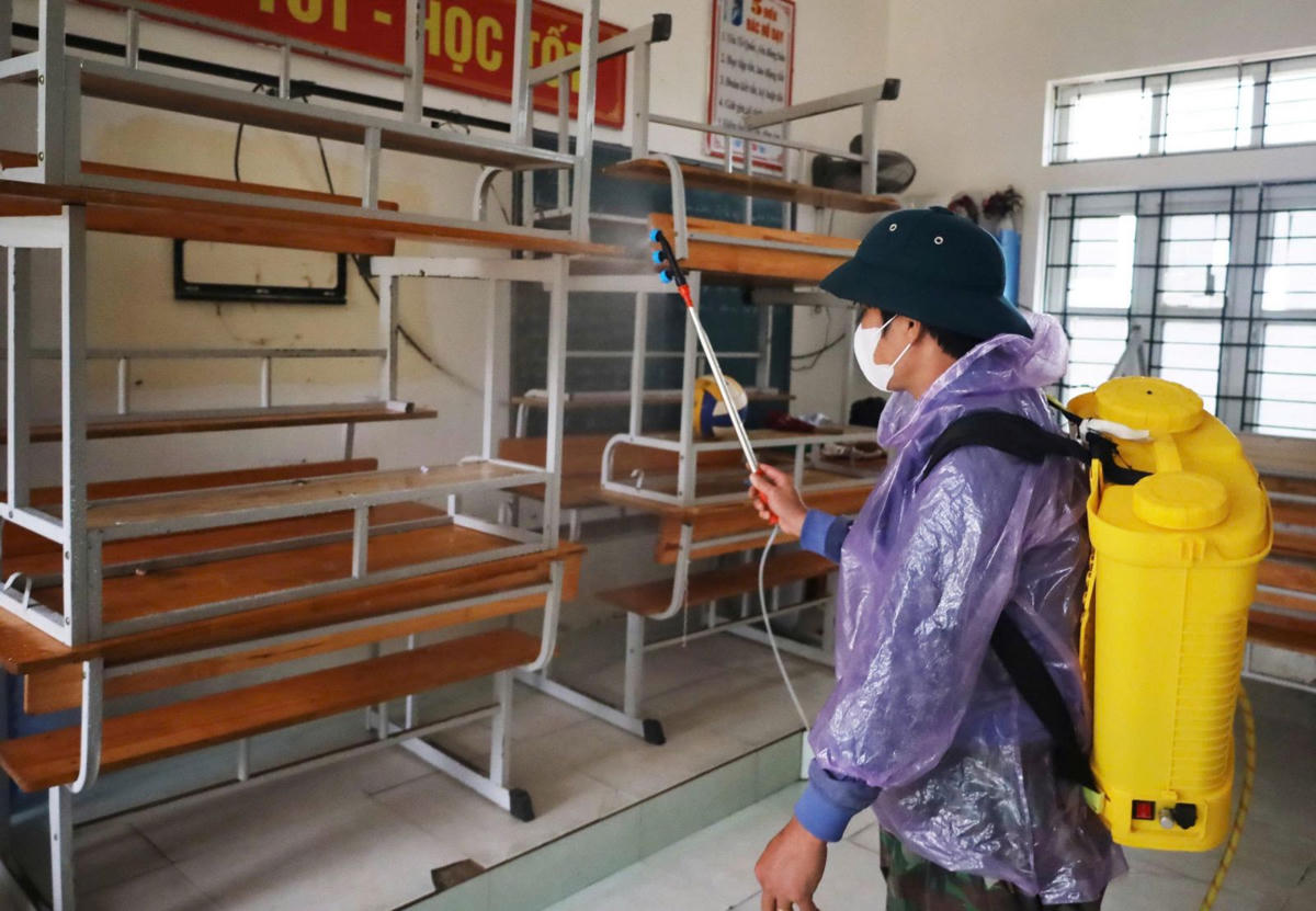 Lực lượng y tế phun hóa chất khử khuẩn bằng Cloramin B tại trường THCS Mỹ Duệ. Ảnh: NT.
