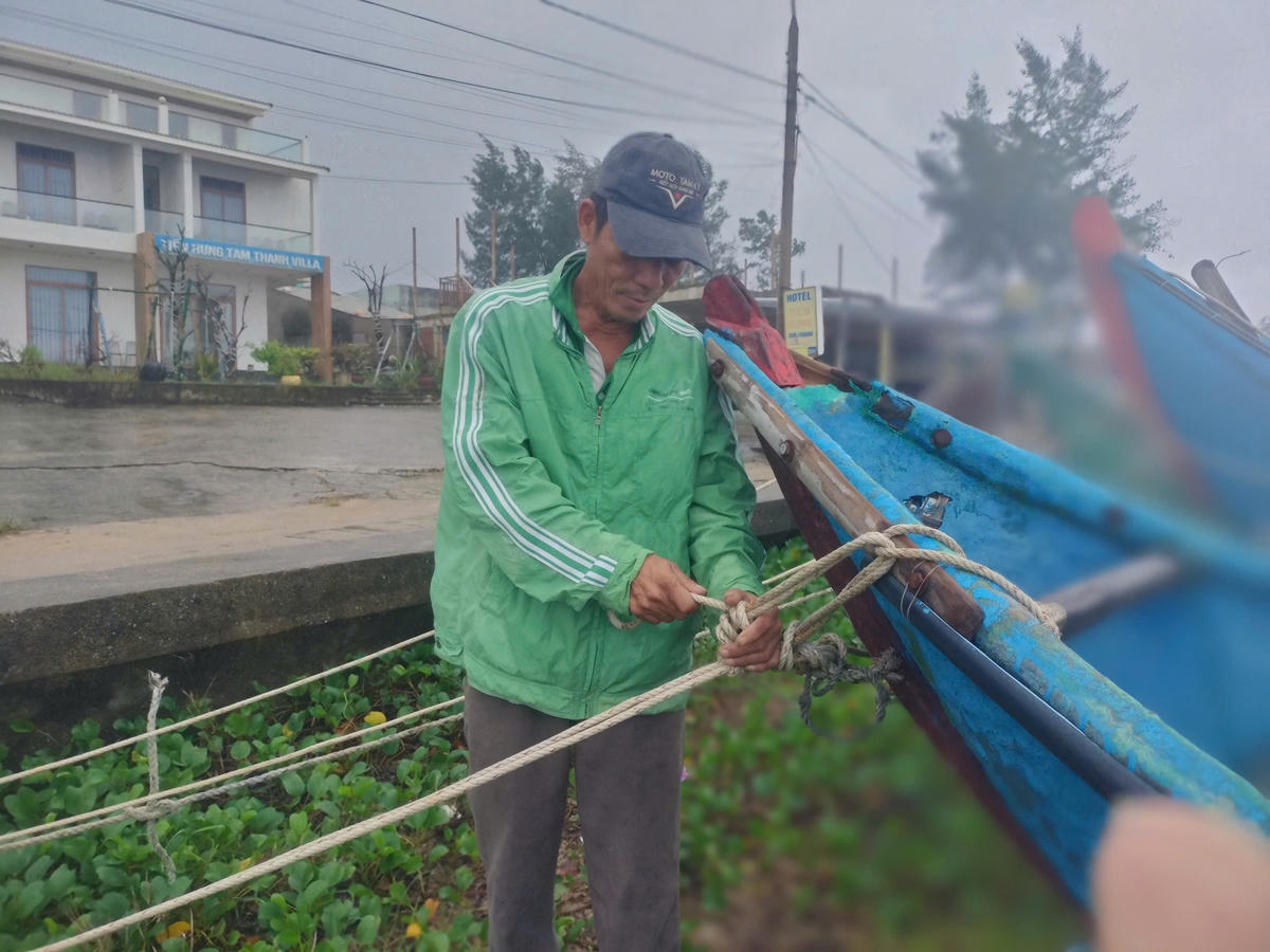 Ngư dân Trần Minh Nhung cột dây chặt ghe thuyền tại bờ kè biển Tam Thanh. Ảnh: CV.