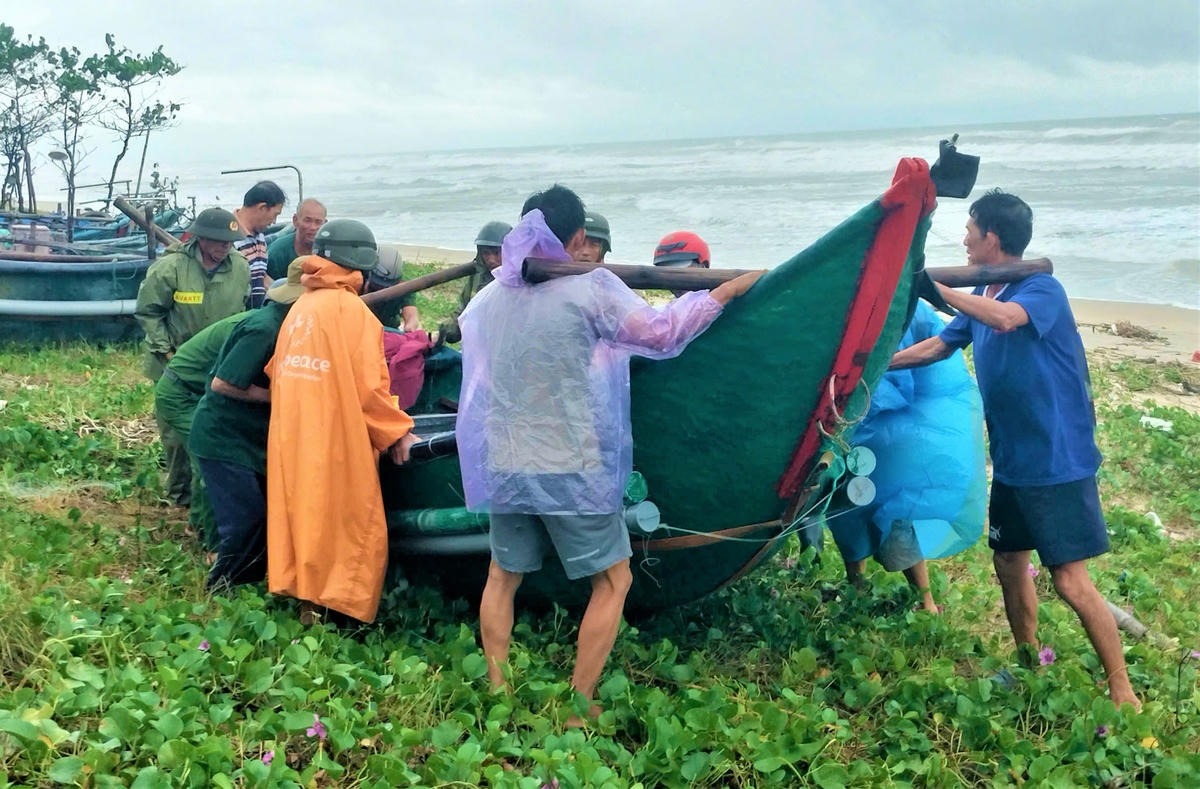Ngư dân cùng lực lượng chức năng phường Quảng Phú đưa ghe lên bờ trú tránh bão số 13. Ảnh: CV.