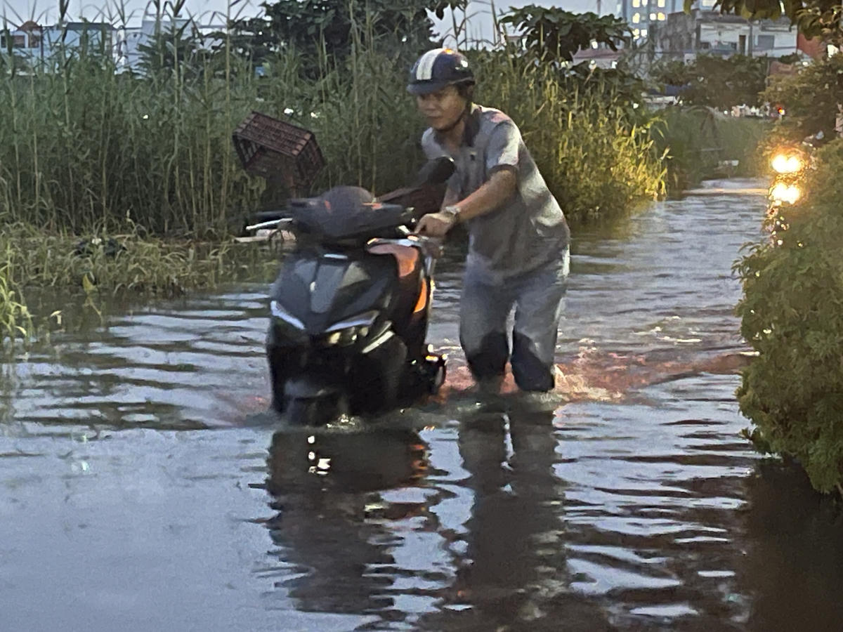Người dân dắt xe lội nước ở đường Rạch Cùng vì triều cường. Ảnh: Đ.Xá.