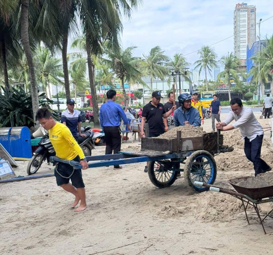 Đưa số cát tràn lên vỉa hè trở lại bờ biển. Ảnh: Nguyễn Tú.