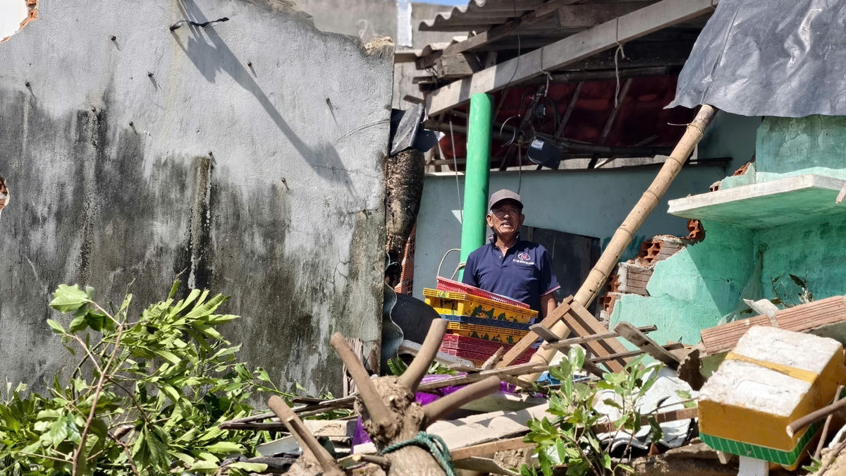 Người dân làng chài chài Xuân Thạnh đứng thẩn thờ nhìn ngôi nhà hư hỏng nặng. Ảnh: Chí Đại.