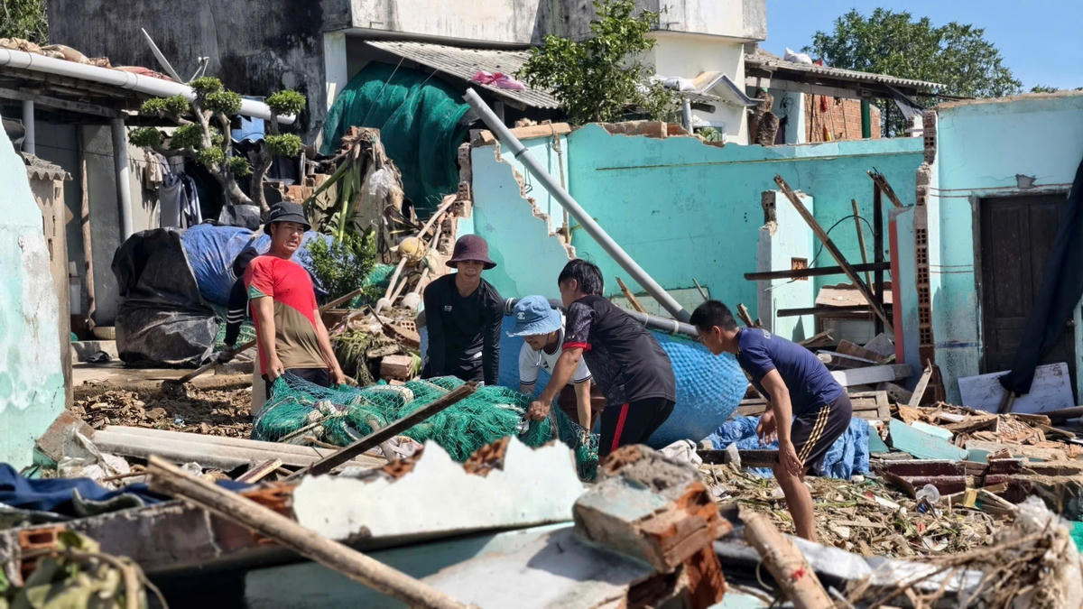 Lực lượng chức năng và người dân làng chài Xuân Thạnh xã Phù Mỹ Đông dọn dẹp đống hoang tàn sau bão. Ảnh Đình Sang.